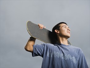 Mixed race teenager standing with skateboard