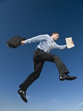 African businessman carrying briefcase in mid-air