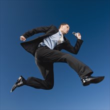 African businessman in mid-air holding cell phone
