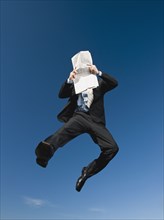 African businessman reading newspaper in mid-air