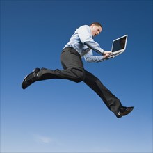 African businessman typing on laptop in mid-air