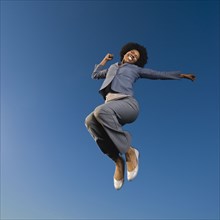 African businesswoman jumping in mid-air