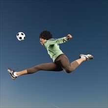 African woman playing soccer in mid-air