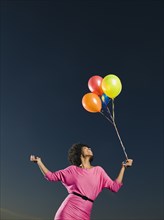 African woman holding bunch of balloons