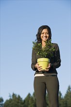 Mixed race businesswoman holding potted plant