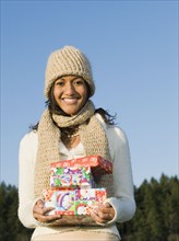Mixed race businesswoman holding Christmas gifts