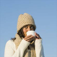 Mixed race woman drinking coffee outdoors