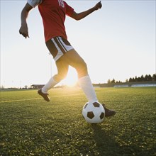 Mixed race woman kicking soccer ball