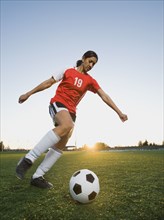 Mixed race woman kicking soccer ball