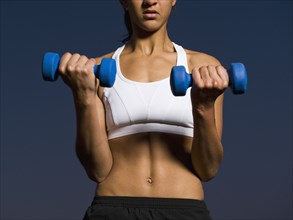 Mixed race woman doing biceps curls with dumbbells