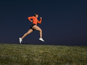 Mixed race woman running on grass