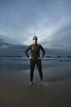 Hispanic woman in wetsuit on beach