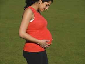 Pregnant Middle Eastern woman looking down at stomach