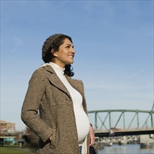 Pregnant Middle Eastern woman standing at waterfront