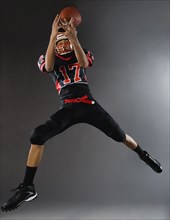 Mixed race football player catching football