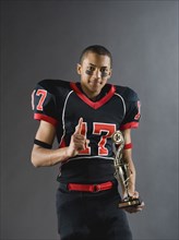 Mixed race football player holding trophy and gesturing