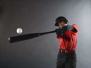 Mixed race baseball player swinging bat