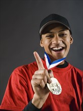 Mixed race baseball player gesturing with award medal