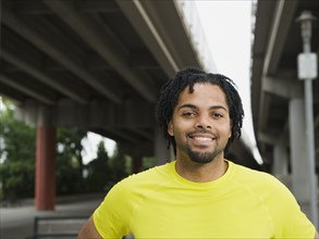 Mixed race man smiling under freeway overpass