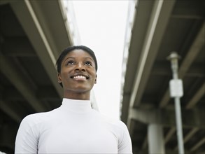 African woman smiling under freeway overpass