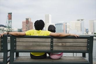 Couple sitting on bench overlooking cityscape