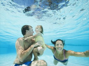 Parents swimming in swimming pool with daughter