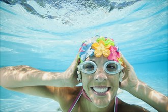 Hispanic woman in retro swimming cap underwater in swimming pool