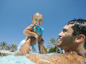 Father swimming in swimming pool with daughter