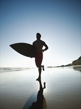 Mixed race man carrying surfboard on beach