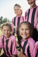 Smiling girl soccer players posing with trophy