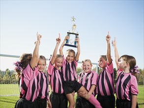 Cheering girl soccer players posing with trophy