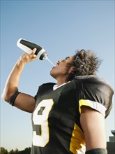Hispanic football player drinking water