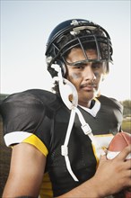Hispanic football player holding football