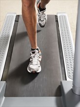 Mixed race man's legs running on treadmill