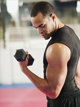 Mixed race man exercising with hand weights in health club