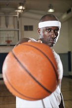 Black man holding basketball on basketball court