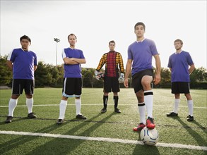 Men standing with ball on soccer field