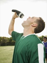 Caucasian soccer player drinking water on soccer field