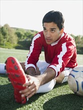 Mixed race soccer player stretching