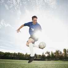 Caucasian soccer player kicking soccer ball