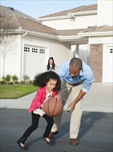 Father and daughter playing basketball in road