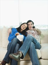 Couple eating popcorn and watching television