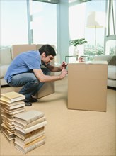 Caucasian man writing on cardboard packing box