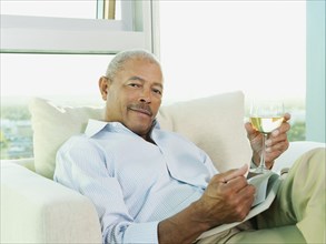 Black man drinking wine and reading book