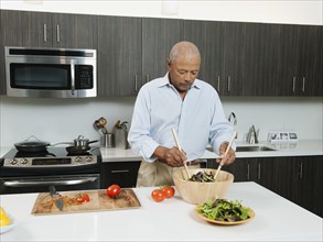 Black man preparing salad in kitchen