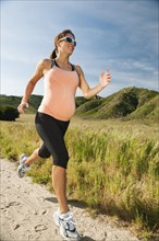 Pregnant Hispanic woman running in remote area
