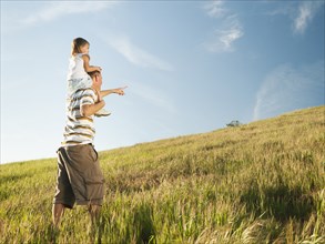 Father carrying daughter on shoulders in field