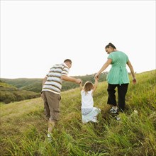 Family holding hands and walking up field