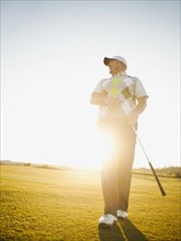 Caucasian man walking on golf course with golf club