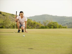 Mixed race woman checking ground on golf course